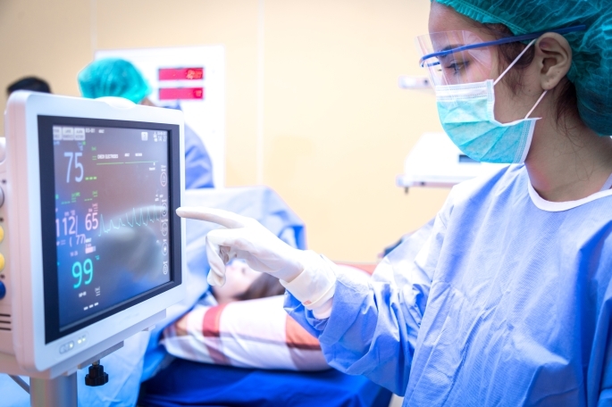 St. John’s University nursing student pointing at a health monitor that shows vital signs.