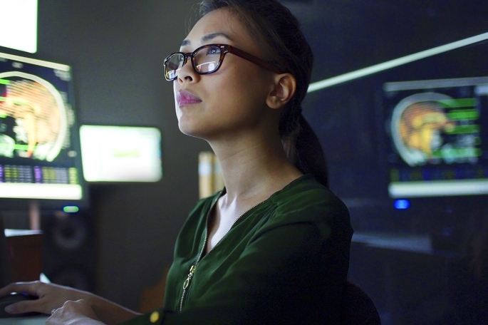 Woman with glasses looking at brain scans on computers