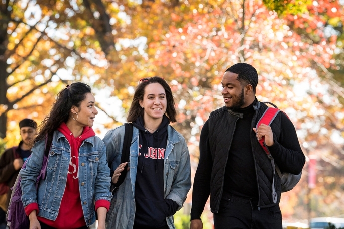 Three students walking outside during a fall day