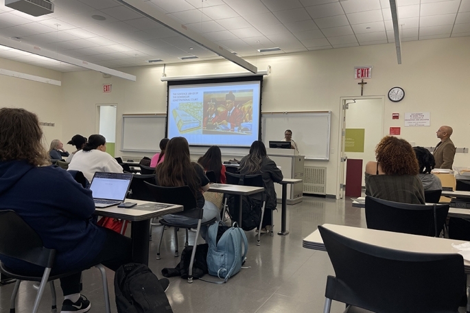 Students seated in a classroom watching projector screen