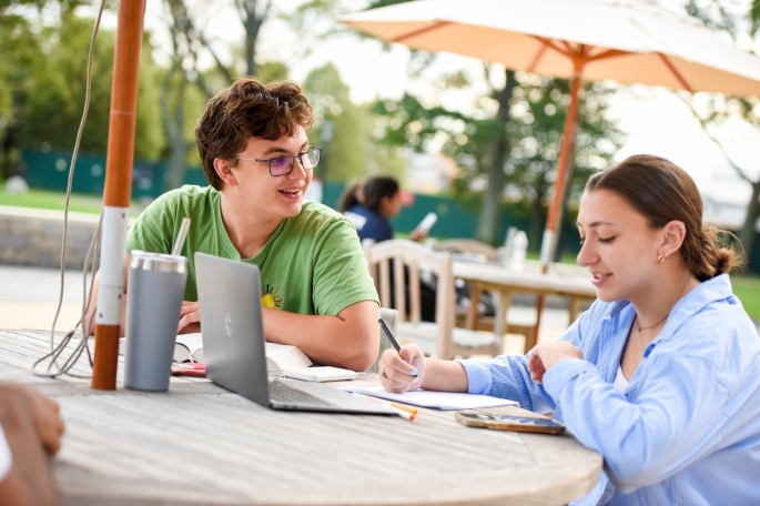 A vibrant campus scene at St. John's University with students socializing on a green lawn, enjoying the lively atmosphere of college life.
