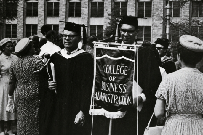 Man holding a sign that says College of Business