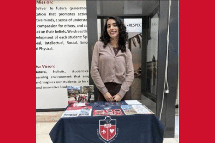 Zeinab El Hawari standing at table with St. John's crest