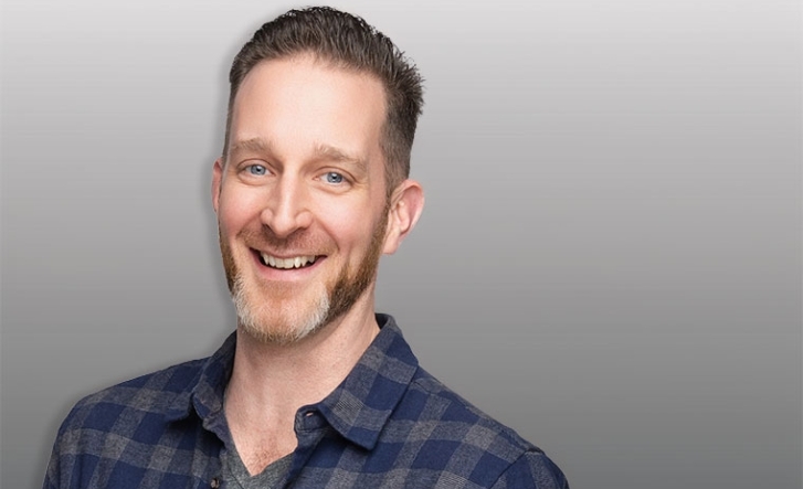 Headshot of a man behind a grey background
