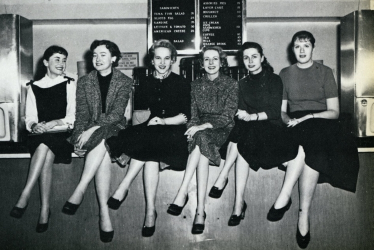 A group of students sitting on the cafeteria counter.