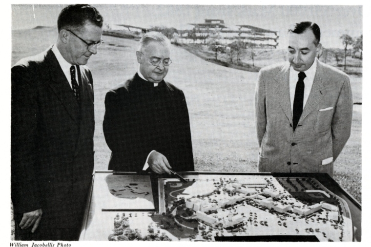 President Flynn shows a model of the Hillcrest campus in Queens to Joseph Kelly '30C (left) and Ernest Haberle '33C (right). The St. John Hall construction site can been seen in the background.