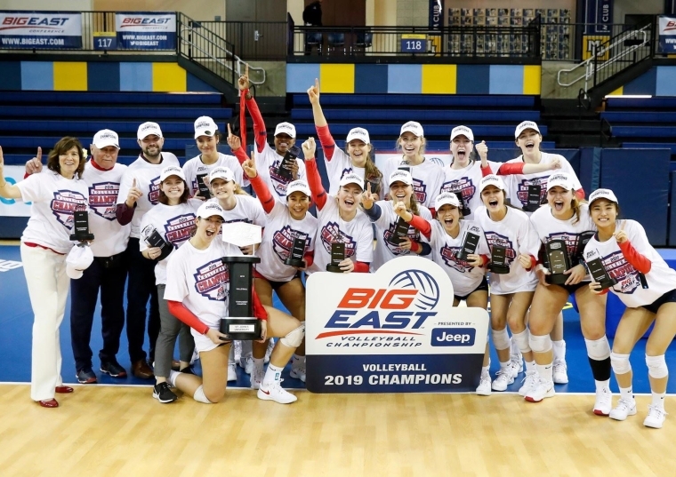 Women's volleyball team poses with big east championship sign