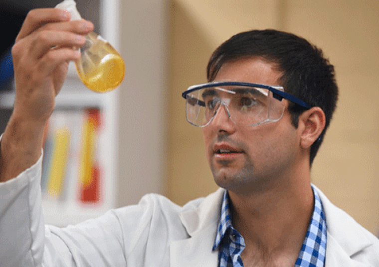 Anthony Tedaldi holding a test tube and wearing chemical goggles
