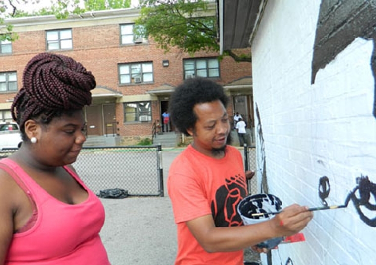 Iandry Randriamandroso painting on a wall