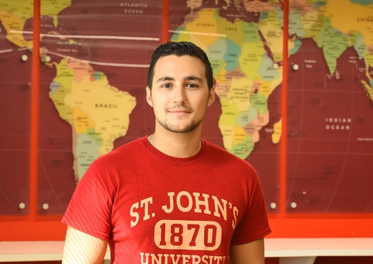 JohnAnthony DiMaria standing in front of world map