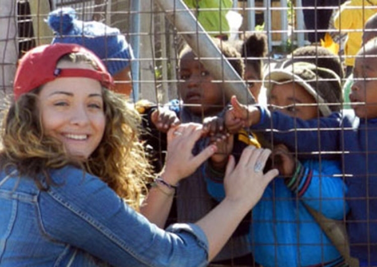 Kerry Andreozzi at a fence with small children on the other side