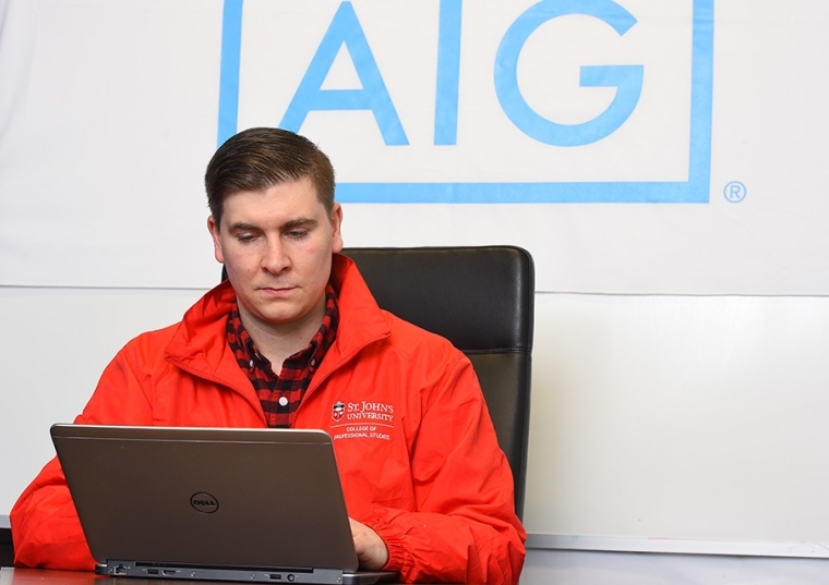 Kevin Kaulfers on his laptop with AIG logo behind him on the wall