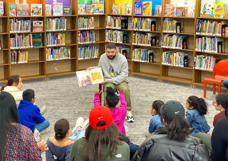 Jorge Santos ’10CPS, ’12G, ’18GEd reading his book to a group of young students