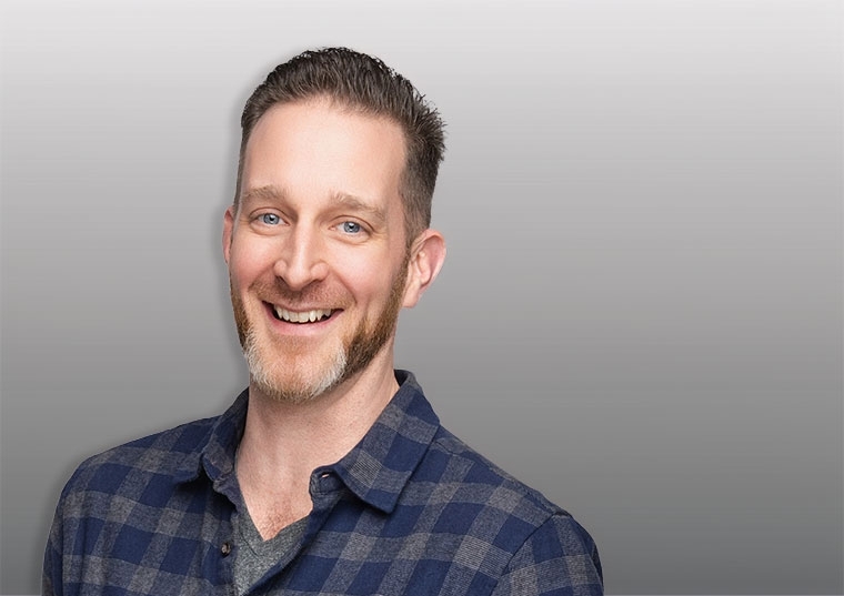 Headshot of a man behind a grey background 