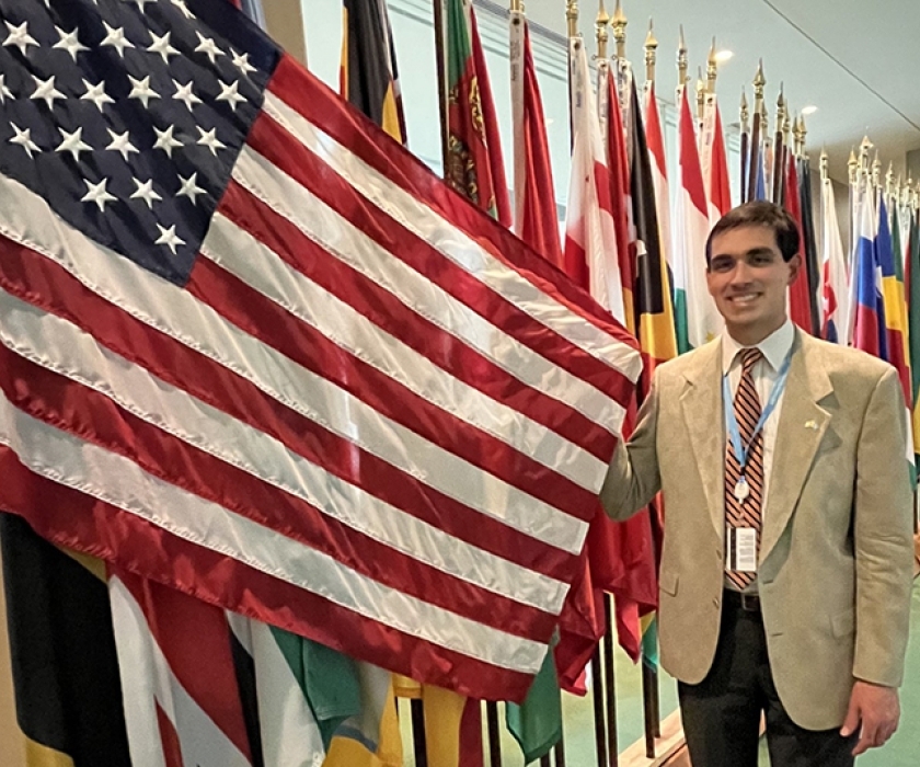 Peter Paolo posing with an American flag next to a row of other national flags