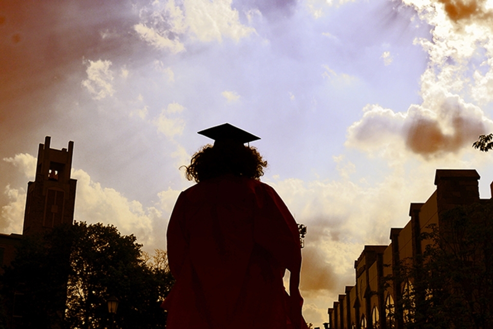 Female student walking away in cap and gown