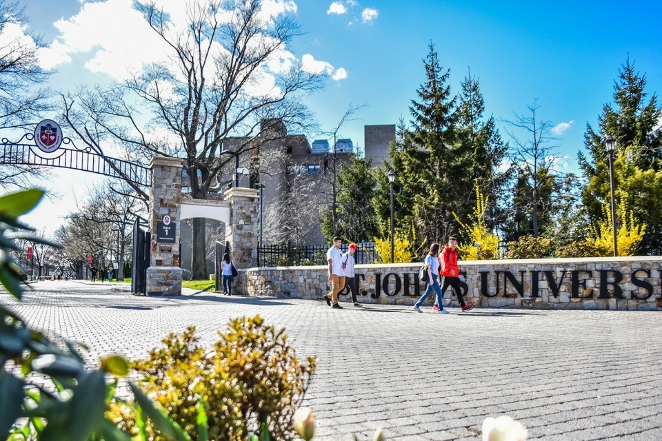 St. John's University front gate with students walking on/off campus