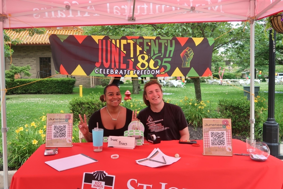 Two women sitting at a table with a Juneteenth Banner