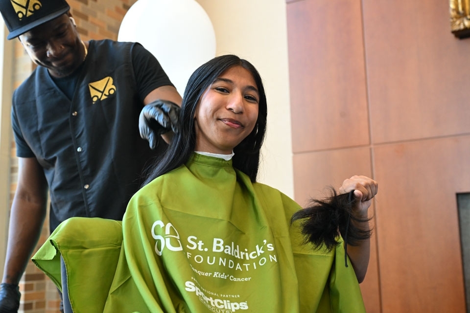 Student sitting in green hairdress gown 