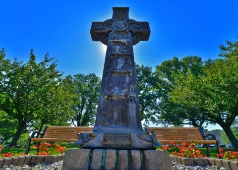 Stone crucifix statue against a blue sky