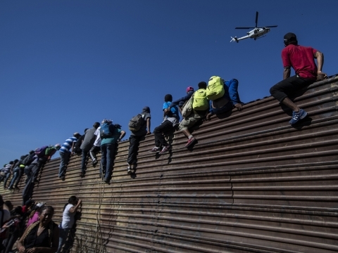 Students sitting on a wall watching a drone in the air