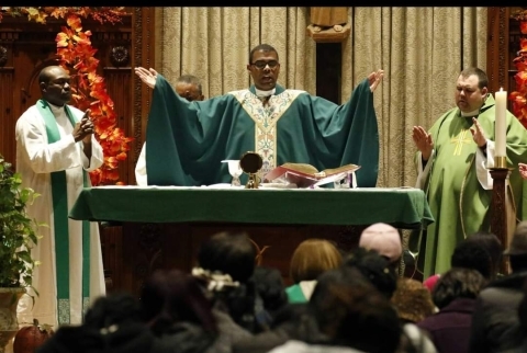 Fr. Alonso Cox raising his hands during church services