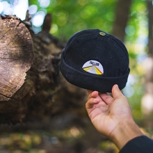 Pallor hat held up in front of a tree trunk