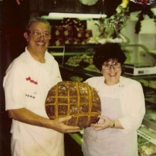 Two Joe's Sicilian Bakery employees holding a round loaf of bread