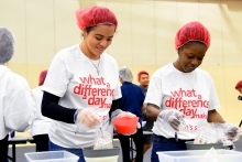 Two women helping package food in assembly line