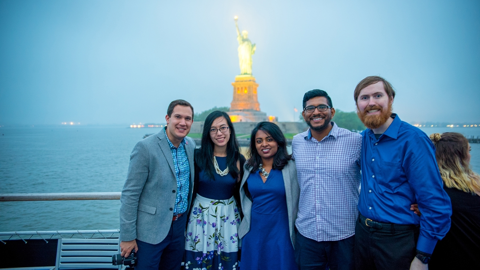 Group of Alumni on boat infront of statue of liberty