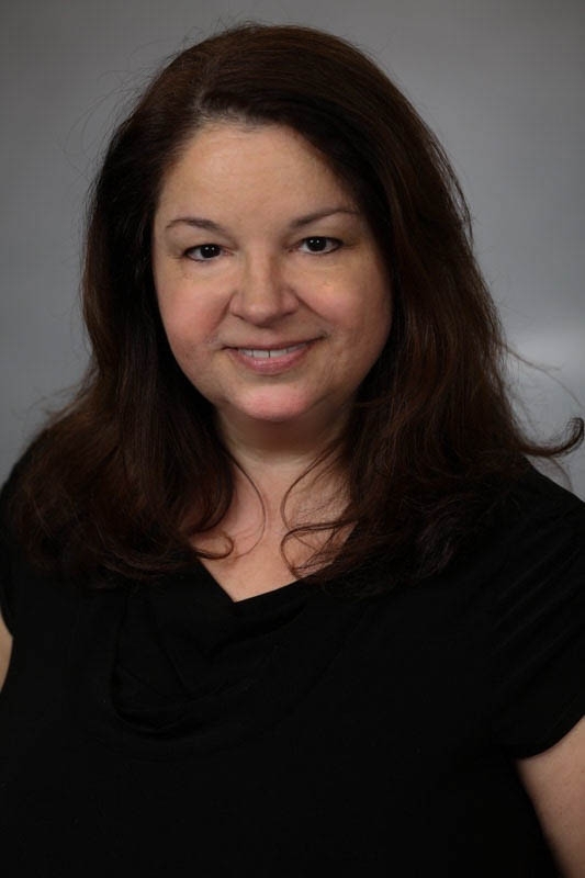 Professional head shot of Professor Louise Lee, with a gray background, wearing a black blouse