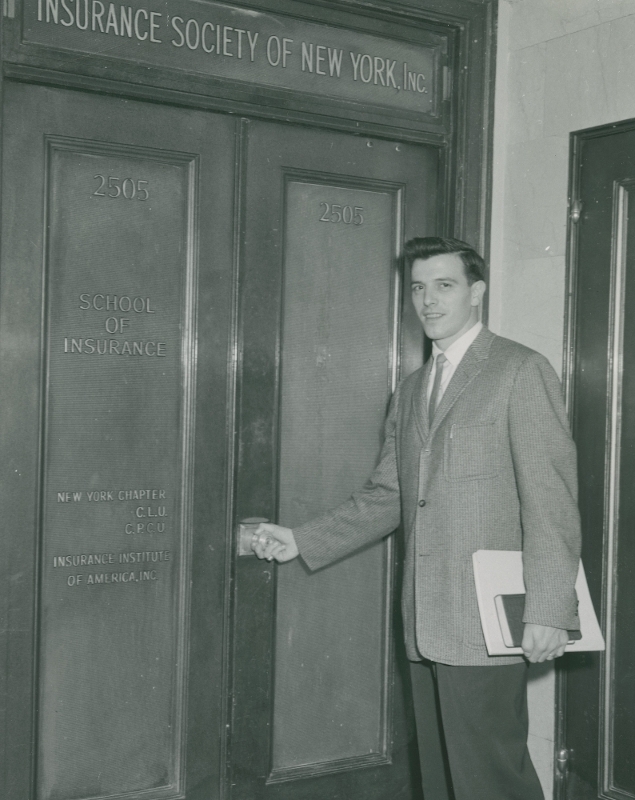 A student walking through the entrance of the Insurance Society of New York on William Street