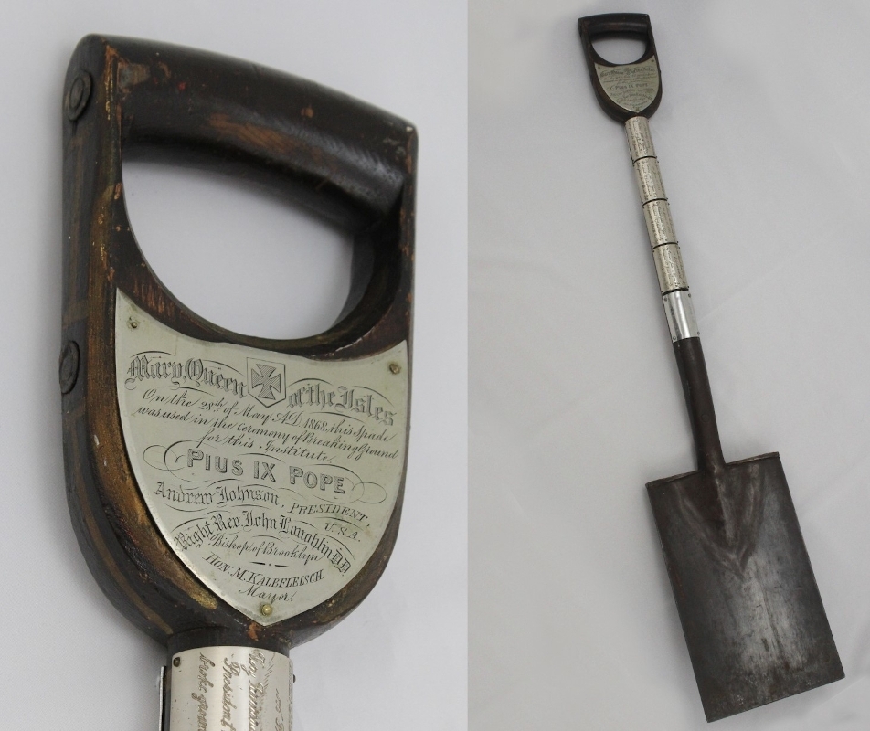 Metal spade with silver plaques on the handle and body, each inscribed with details of groundbreaking ceremonies