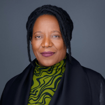Headshot of Valerie Capers Workman wearing a green patterned shirt and a black jacket.