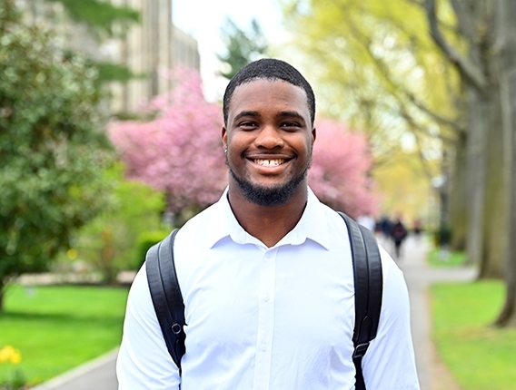 Male grad student smiling outside during springtime